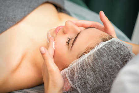 Spa facial skincare. Close-up of a young caucasian woman getting spa moisturizing face massage treatment at beauty spa salonの写真素材