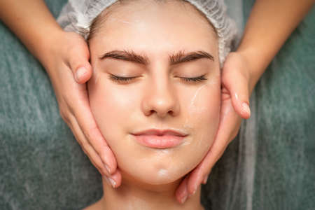 Spa facial skincare. Close-up of a young caucasian woman getting spa moisturizing face massage treatment at beauty spa salonの写真素材