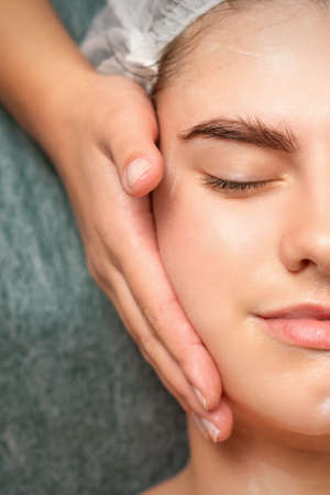 Spa facial skincare. Close-up of a young caucasian woman getting spa moisturizing face massage treatment at beauty spa salonの写真素材