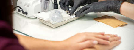 Hands in black gloves of manicurist preparing special nail file equipment for manicure treatment in a beauty salonの写真素材