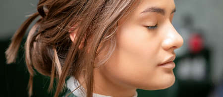 Portrait of a sensual young caucasian woman with closed eyes showing makeup tan on her face and hairstyle in a beauty salonの写真素材