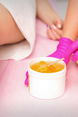 Beautician with a white jar of wax sugaring before hair removal at the spaの写真素材