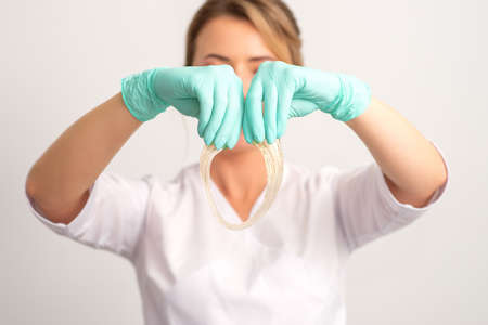 Young caucasian smiling female beautician holding wax for depilation over white background. Yellow sugar paste in hands master of depilation. Epilation conceptの写真素材