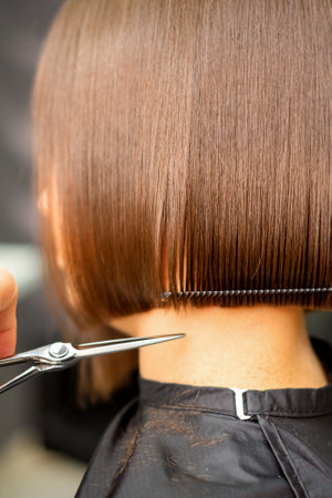 Haircut of short hair of young white woman by hands of a hairdresser in a hair salon, back view, close upの写真素材
