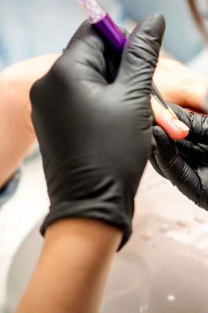 Manicure painting art. Manicure master drawing on the nail tip with a thin brush, close upの写真素材