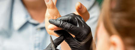 Manicure painting art. Manicure master drawing on the nail tip with a thin brush, close upの写真素材