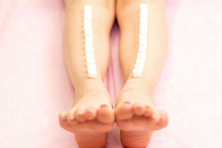 The concept of epilation, waxing. Sugar cubes lie down in a row on the naked white female legの写真素材