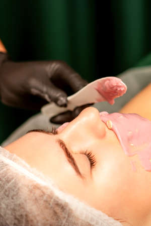 Beautiful young caucasian woman receiving an alginic mask to the face in beauty salon. Facial skin treatmentの写真素材