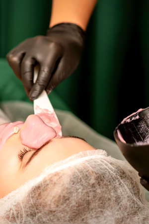 Beautiful young caucasian woman receiving an alginic mask to the face in beauty salon. Facial skin treatmentの写真素材