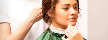 Makeup artist and hairdresser prepare the bride making hairstyle and makeup in a beauty salon
