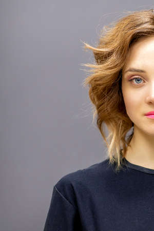 Portrait of a beautiful young caucasian red-haired woman with short wavy hairstyle smiling and...