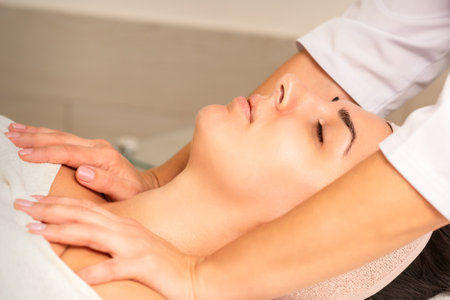 Young caucasian woman with closed eyes getting a chest massage in a beauty clinicの写真素材