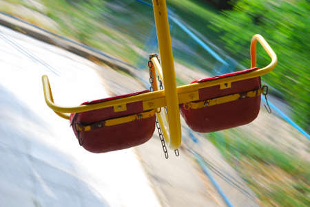 Empty seats of merry-go-round turnning against summer blurred backgroundの写真素材