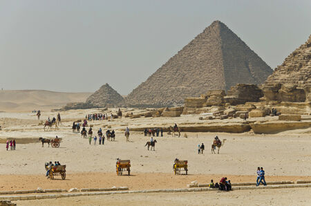 Tourists and natives are near ancient Egyptian pyramids  The Giza Necropolis has been a popular...