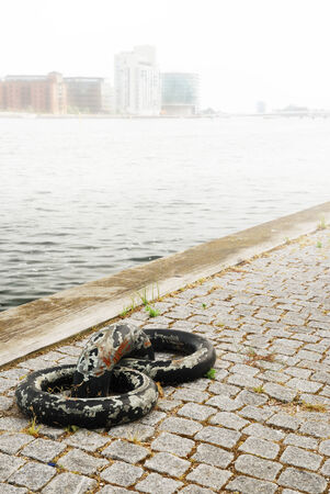 The canal is fogged in  In the foreground heavy mooring rings are on the cobbled quay  In the background there are buildings in the thick mist の写真素材
