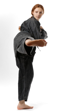 A teenage girl kicks her right legs  She is wearing a black kimono の写真素材