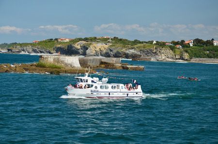 Saint-Jean-de-Luz is a famous resort on the Basque coast  A stony bottom of the sea is uncovered at reflux  A small lighthouse is on the green hill のeditorial素材
