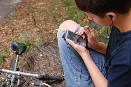 Teenage boy is holding an electronic device and using a stylus の写真素材