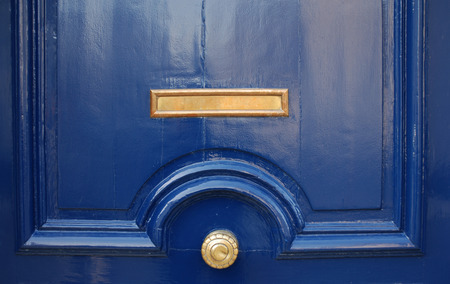 Shining surface of massive blue door decorated golden mail slot and round handle, close-upの写真素材