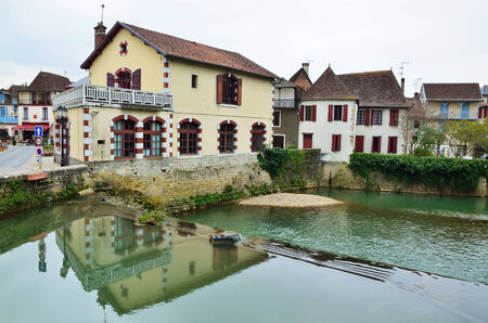 The old stone houses with sloping roofs and shutters are reflected in the water surface of the traditional French town in Aquitaine region.のeditorial素材