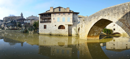 The medieval buildings and the old bridge are reflected on the mirror surface of the calm river Baise in the town Nerac.の写真素材