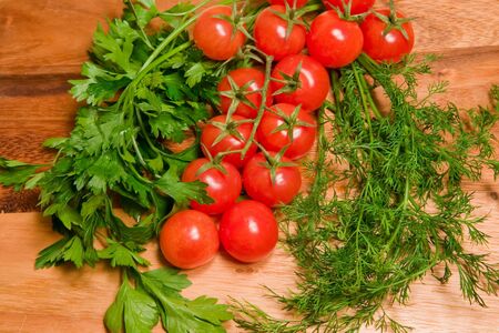 Tomatoes,  dill and parsley on a kitchen wooden boardの写真素材