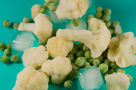 Cauliflower and green peas with ice on a blue backgroundの写真素材