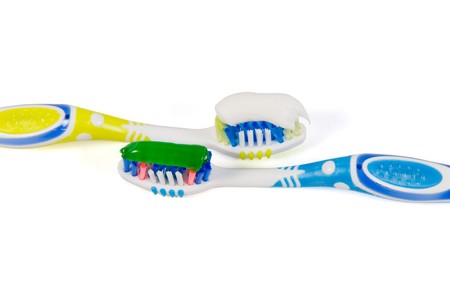 Two tooth-brushes with different paste on a white background