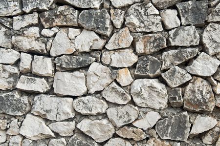 Straight-on close-up view of a rock wall of stacked, natural field stonesの写真素材