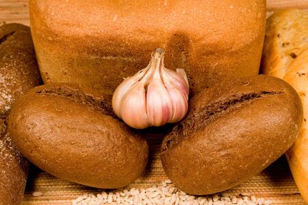 Garlic, wheaten and rye bread on a straw clothの写真素材