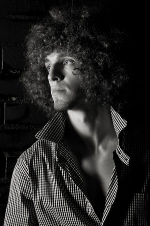 Portrait young man with a curly hair against a black wallの写真素材