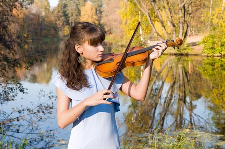 The young woman with a violin listens to music of autumnの写真素材