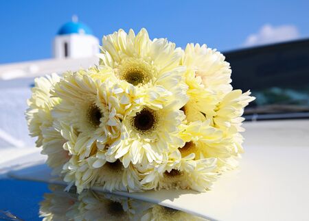 Bouquet of yellow chrysanthemums on the hood of the car. In the background of the Greek Church.の写真素材