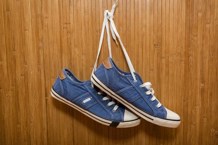 Blue, new, denim sneakers hanging on a bamboo wallの写真素材