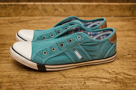 Pair of green canvas sneakers are on the yellow wood floorの写真素材