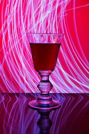 Glass of red wine on the background of abstract lighting backgroundの写真素材