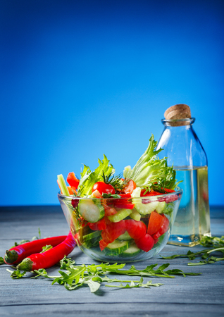 Bowl of salad with fresh vegetables and olive oil on wooden backgroundの写真素材