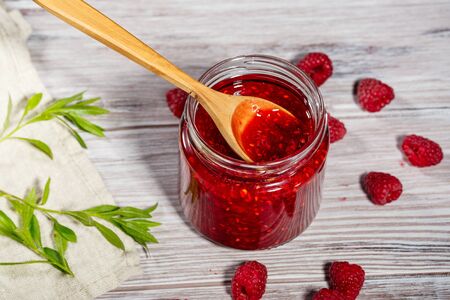 Homemade jam and fresh raspberry on wooden background