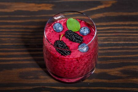 Glass of fresh smoothie with  berries on a dark wooden backgroundの写真素材