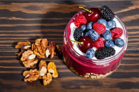 Breakfast with oatmeal, fresh fruit and walnuts on a dark wooden tableの写真素材