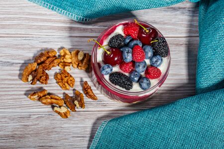 Breakfast with fresh berries, muesli and nuts on a light wooden backgroundの写真素材