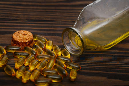 Omega 3 capsules and fish oil on a dark wooden backgroundの写真素材