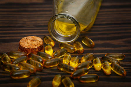 Omega 3 capsules and fish oil on a dark wooden background