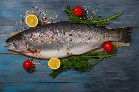 Large, fresh trout and vegetables on a dark blue wooden backgroundの写真素材