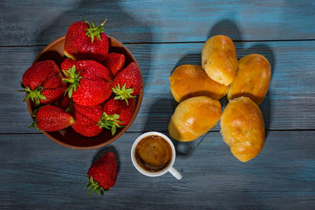 Fresh pies, a plate of strawberries and coffee on a blue wooden tableの写真素材