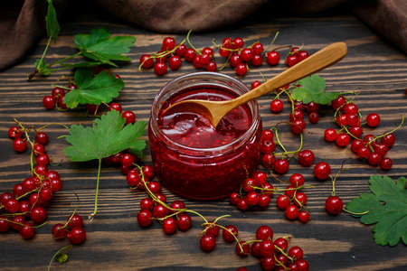 Jam and red currant berries on a dark, wooden backgroundの写真素材