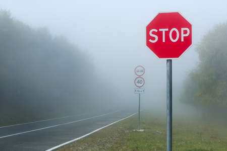 Dangerous fog on the road in the mountains, speed limit road signの写真素材