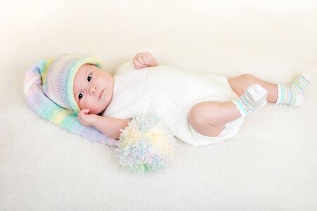 infant baby weared funny hat lying on a blanketの写真素材