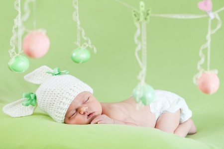adorable baby dressed in Easter bunny cap with eggsの写真素材
