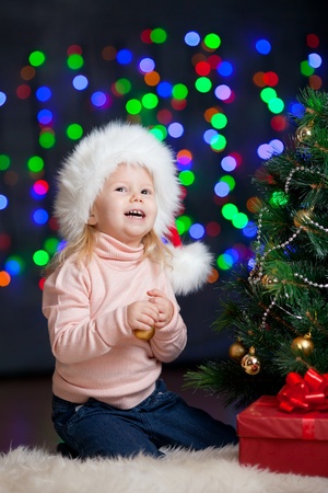 pretty preschool girl decorating Christmas tree over bright festive backgroundの写真素材